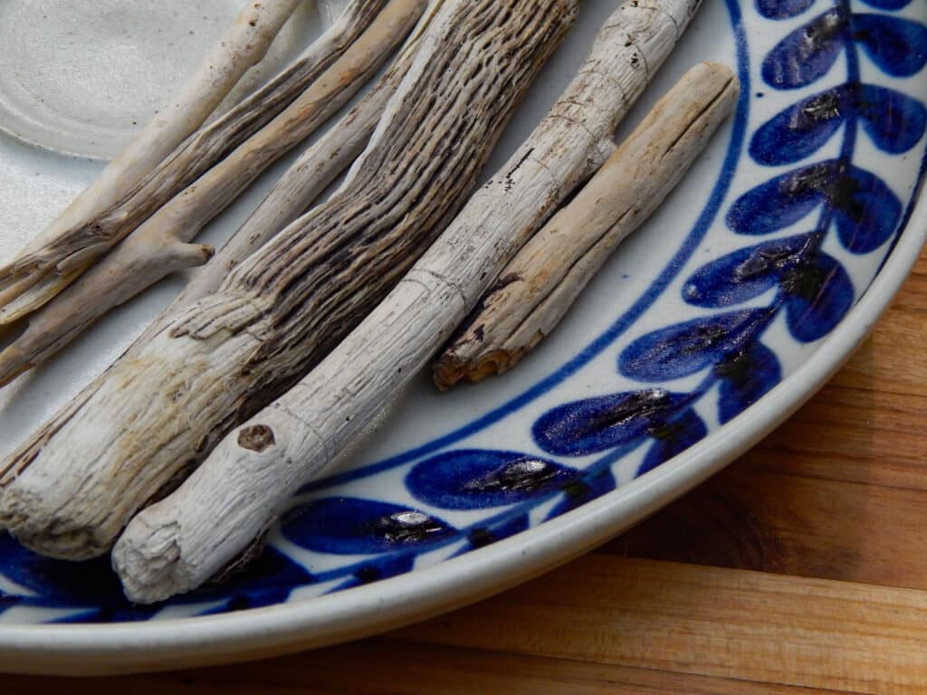 close up of driftwood collected sensory bin rough texture with different sizes in a pottery platter with blue design