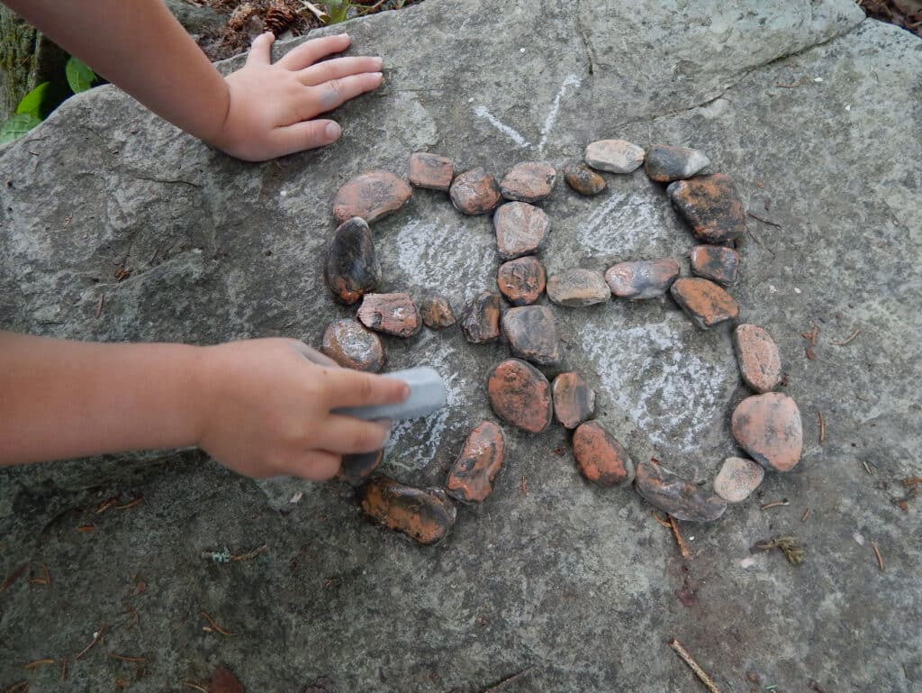 little hands making spring craft with chalk rocks and water outside