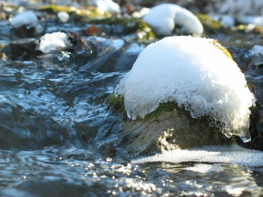 stream thawing with snow still on top of rocks