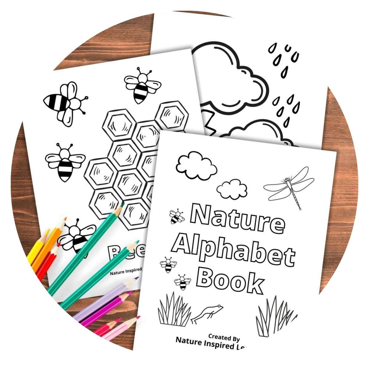 nature alphabet book cover with two sheets overlapping on a wooden background. Colored pencils bottom left on top of pages