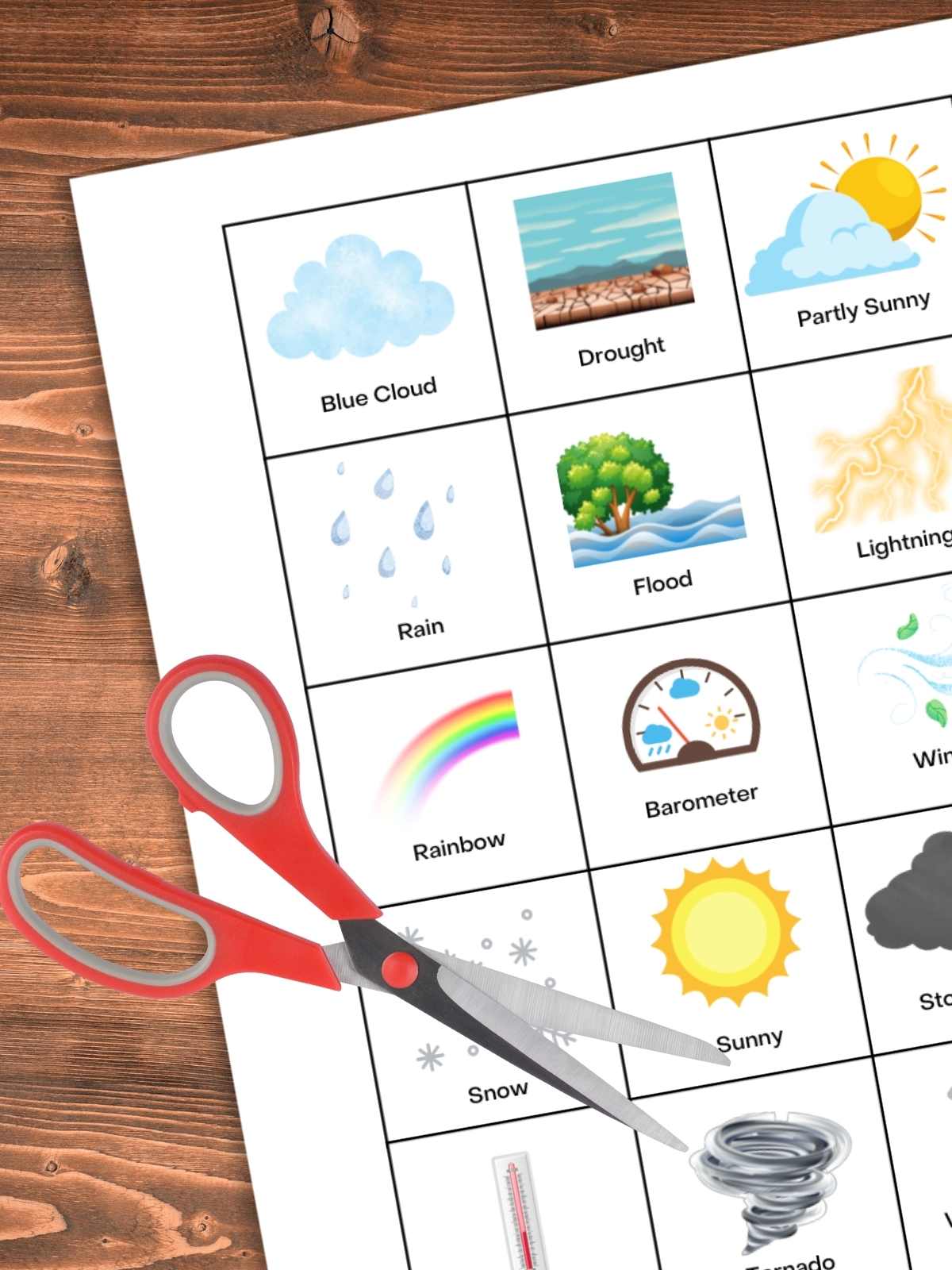 bingo calling cards with images of weather events and tools label under the images. Red scissors on top of printable on a wooden background