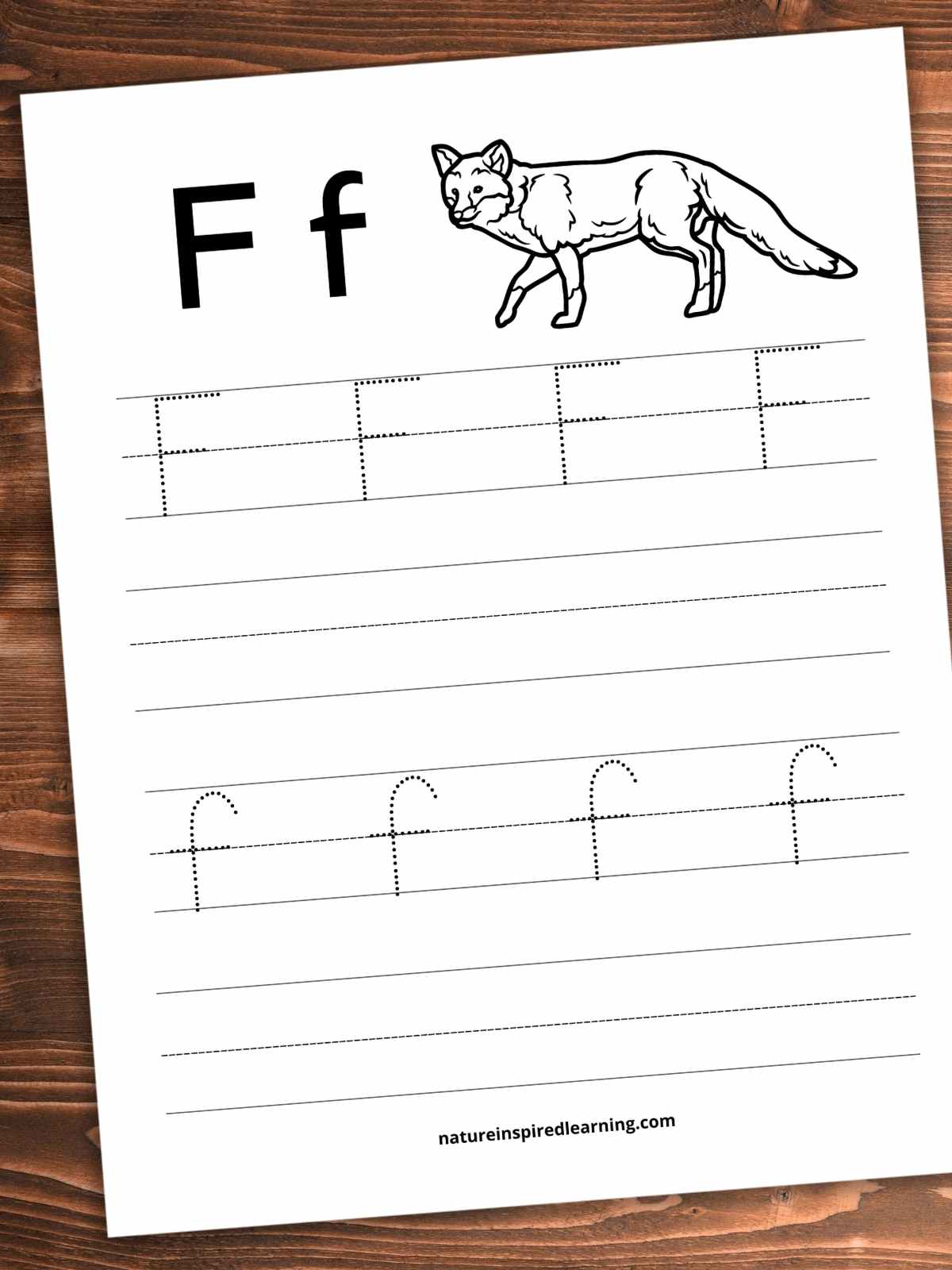 Worksheet slanted on a wooden background. F f with a black and white fox on the top with lines with four traceable F's a bank set of lines below, then traceable f's with a set of blank lines below.