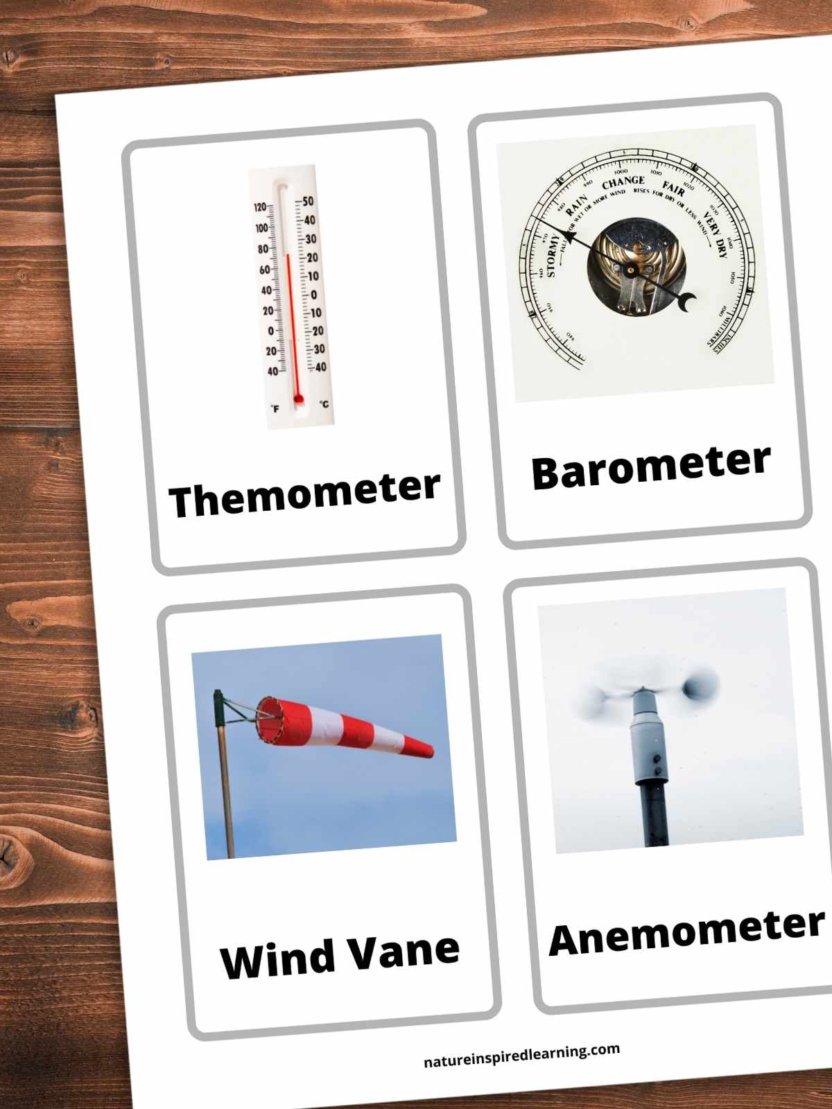 printable weather flashcards with weather tools including thermometer, barometer, wind vane, and anemometer vocab word written on each card below an image. Printable on a wooden background