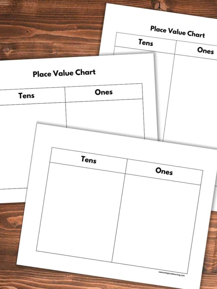 three basic black and white tens and ones place value charts overlapping on a wooden background