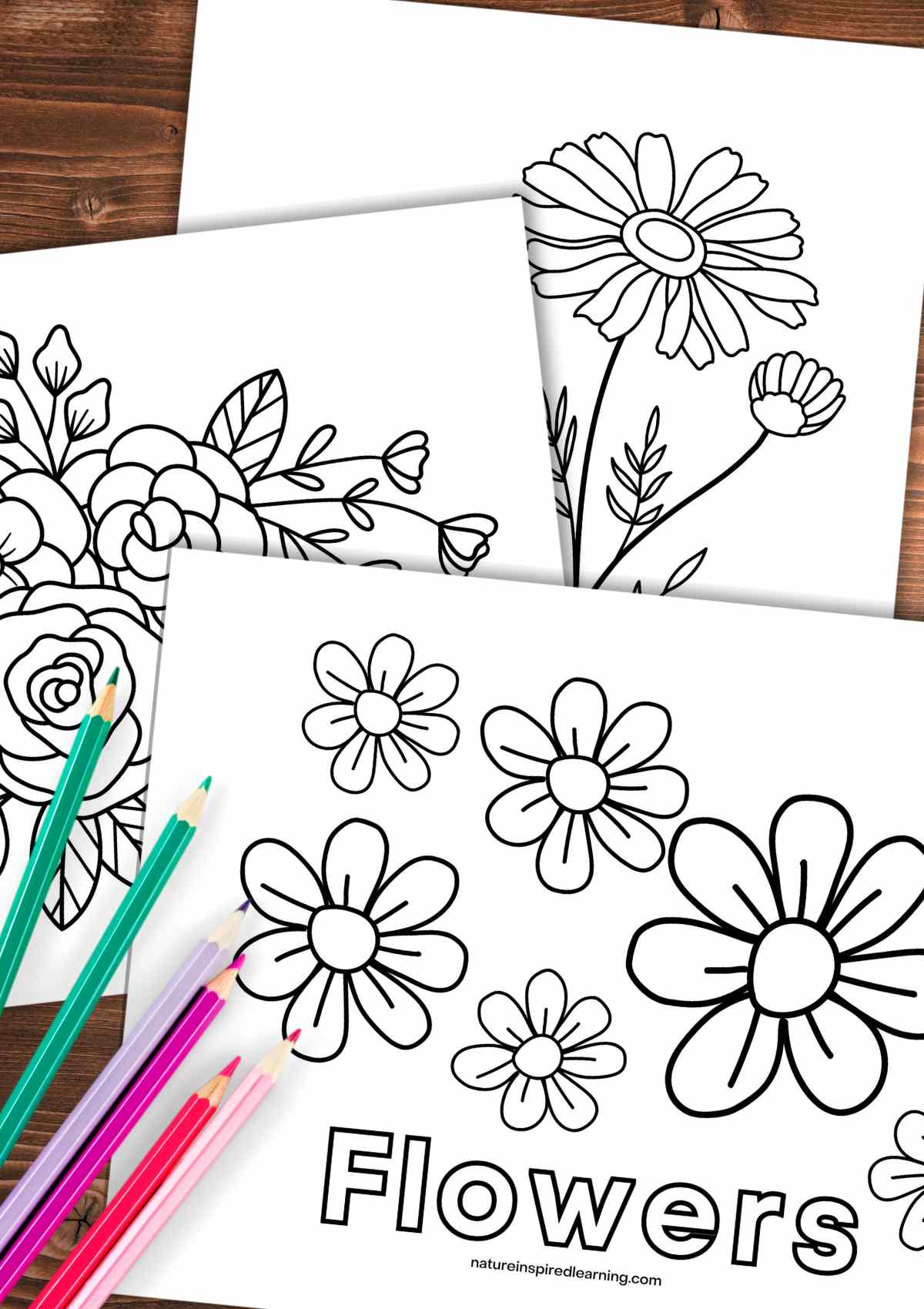 three coloring sheets with different flower designs overlapping on a wooden background with colored pencils on the bottom left corner.